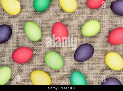 Background with multicolored easter eggs on a burlap. Stock Photo