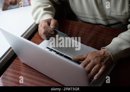 Smiling senior man wear earphones wave to camera having video call on laptop, happy elderly male in headphones sit on couch at home talk using modern Stock Photo