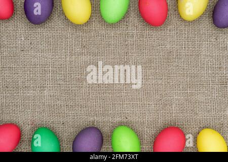 Multicolored Easter eggs on a burlap background. Easter frame. Stock Photo