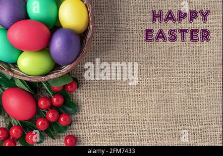 Easter eggs in a wicker basket, red berries and the inscription "Happy Easter". Stock Photo