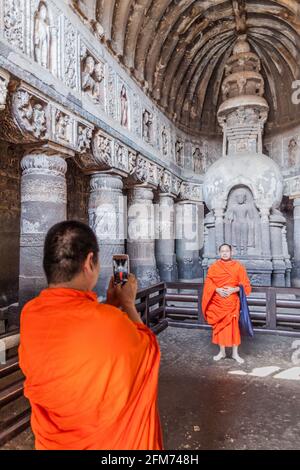 AJANTA, INDIA - FEBRUARY 6, 2017: Buddhist monks taking photos in the chaitya (prayer hall), cave 19, carved into a cliff in Ajanta, Maharasthra state Stock Photo