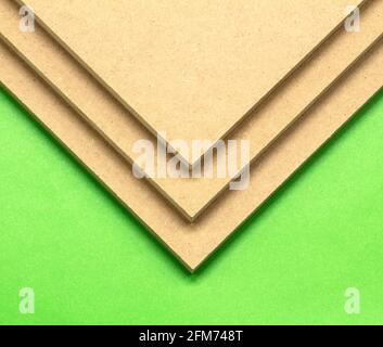 Three boards of raw MDF on a green background. They can be used in the construction industry. Stock Photo