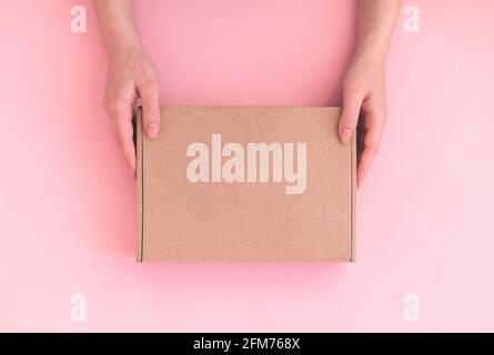 Delivery woman hold parcel box with copy space on pink background, mockup template of cardboard box Stock Photo