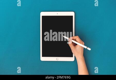 Kharkov, Ukraine - May 5, 2021: Woman using Apple iPad mockup with pencil stylus pen, colorful background and top view Stock Photo