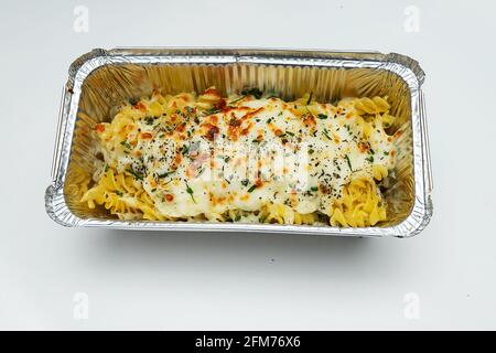 hot Italian macaroni in a disposable dish for food delivery, high-calorie fast food pasta on a white background Stock Photo