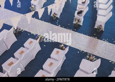 Wedding aisle with white chairs and white carpet from above with bunting and petals Stock Photo