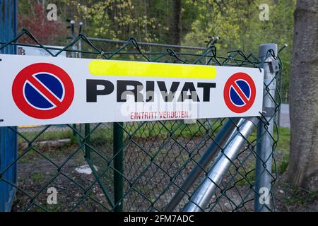 A sign on a wire fence with an inscription indicating private property and a parking ban. Stock Photo