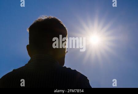 Silhouette of a man looking at the sun in the blue sky Stock Photo