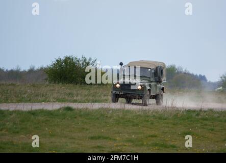 a British Army Land Rover Defender hurtles along a dusty stone track, on maneuvers Stock Photo