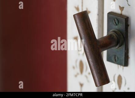 Background image of metal handle of an old white window and a part of the facade in burgundy red Stock Photo