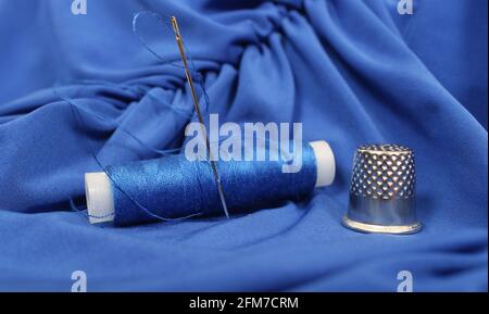 Thimble and Blue Thread on Blue Fabric Stock Photo