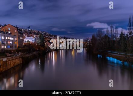 Blue hour in Zürich, the largest city in Switzerland. Illuminated houses along the Limmat River and their reflections in the water Stock Photo