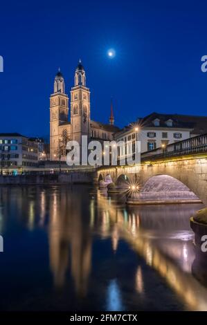 Munsterbrucke and Grossmunster church reflecting in the blue hour in river Limmat, Zurich, Switzerland Stock Photo