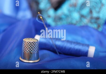 Thimble and Blue Thread on Blue Fabric Stock Photo
