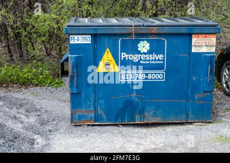 Ottawa, Ontario, Canada - May 1, 2021: A dumpster maintained by Waste Connections of Canada (formerly Progressive Waste Solutions) sits in a gravel pa Stock Photo