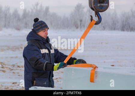 The slinger installer puts a tape rag rope on the hook Stock Photo - Alamy