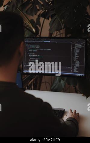 Developer is coding using screen and tablet. Freelancer is working from home Stock Photo