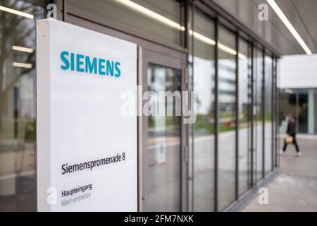 PRODUCTION - 30 April 2021, Bavaria, Erlangen: The lettering logo of the German industrial corporation Siemens, stands on a stele at the entrance of an office building on the Siemens Campus Erlangen. Office and administrative workplaces as well as the research and development of Siemens in the region are concentrated on the campus, but the Friedrich-Alexander University Erlangen-Nuremberg (FAU) or Framatome (nuclear technology) are also represented there. The part that has already been completed, Module 1, is home to Siemens Mobility, Siemens Global Business Services, the Siemens CFO, the Siem Stock Photo