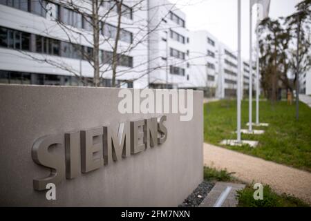 PRODUCTION - 30 April 2021, Bavaria, Erlangen: The lettering logo of the German industrial corporation Siemens, stands on a stele at the entrance to the Siemens Campus Erlangen. Office and administrative workplaces as well as the research and development of Siemens in the region are concentrated on the campus, but the Friedrich-Alexander University Erlangen-Nuremberg (FAU) or Framatome (nuclear technology) are also represented there. The part that has already been completed, Module 1, is home to Siemens Mobility, Siemens Global Business Services, the Siemens CFO, the Siemens Central Franconia Stock Photo