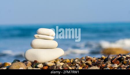 Stones balance, vintage retro instagram like hierarchy stack over blue sea background. Spa or well-being, freedom and stability concept on rocks. Stock Photo