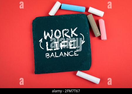 Work and Life Balance. Chalk board and colored pieces of chalk on a red background. Stock Photo
