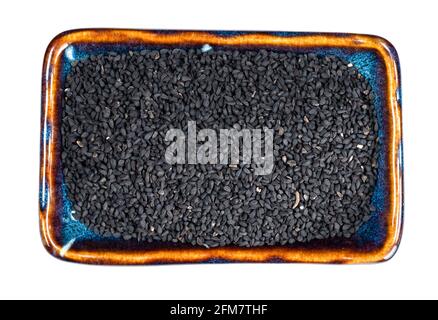 top view of Nigella sativa seeds (black caraway) in ceramic bowl cutout on white background Stock Photo