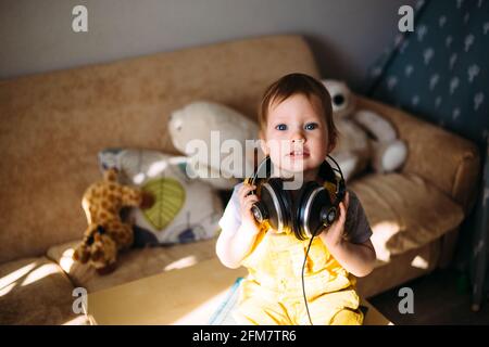Funny little child having fun with headphones at home, portrait. Stock Photo