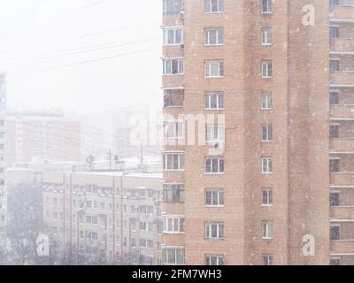 falling snow and apartment houses in city on overcast winter day in Moscow, Russia Stock Photo