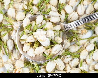 top view of silver spoon on pile of dried jasmine blooms closeup Stock Photo