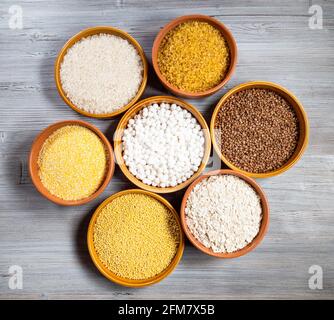 top view of raw groats in round ceramic bowls on gray wooden table Stock Photo