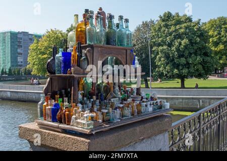 Collection of vintage clear vessels in shades of blue, green and brown on a vintage wooden street vendor's rack near by Honey bridge over the Pregolya Stock Photo