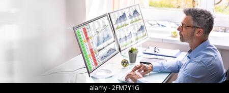 Stock Exchange Analyst Using Multiple Computer Screens Stock Photo