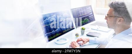 Stock Exchange Analyst Using Multiple Computer Screens Stock Photo