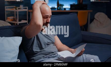 Worried anxious young man reading bad message in postal letter, get eviction, dismissal notice, feeling desperate, depressed, helpless frustrated. Stress victim has troubles with unpaid banking bills Stock Photo