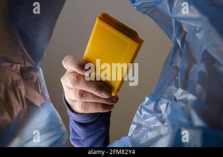 The hand throws the yellow video game cartridge into the trash. A man holds TV game cartridge over an trash can. Bottom view. Indoors Stock Photo