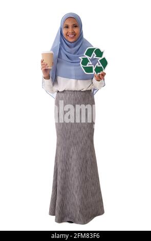 environment, eco living and sustainability concept - full length portrait of happy smiling young asian muslim woman holding green recycling sign and t Stock Photo
