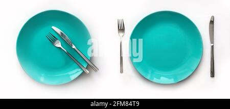 Served plates with cutlery. Empty green plates and stainless knives and forks isolated on white background. Top view. Studio shot Stock Photo