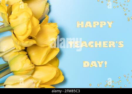 Horizontal banner with yellow tulip flowers on a blue background with the inscription Happy Teacher's Day. Congratulations on the holiday day of the t Stock Photo