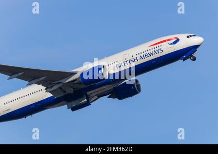 British Airways Boeing 777 jet airliner plane G-YMMD climbing out after take off from London Heathrow Airport, UK, in blue sky. Taking off Stock Photo