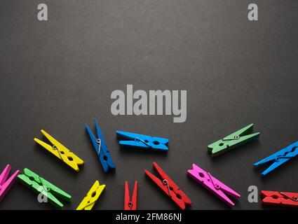 Mini colorful wooden craft pegs flat lay on black dark grunge texture pattern abstract background. Free space for your design. Top view, no people. Stock Photo