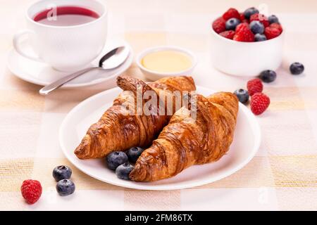 Fresh Baked Croissants Served On A Breakfast Table With Hot Fruit Tea Raspberry Honey And Blueberry. Stock Photo