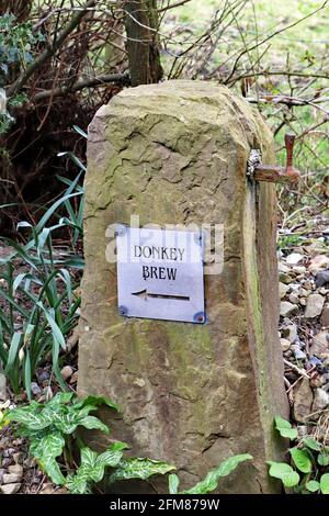 On the West Pennine Moors are lots of public footpaths.  This old stone gate post has a direction sign to one of the footpaths called Donkey Brew. Stock Photo