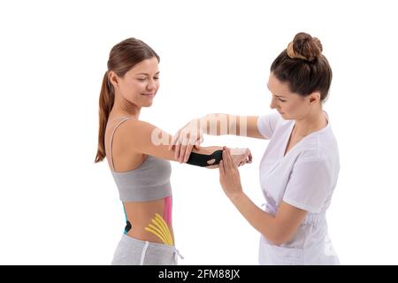 Physiotherapist applying kinesio tape on female patient's arm. Kinesiology, physical therapy, rehabilitation concept. Tennis or golfers elbow treatmen Stock Photo
