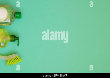 Cleaning products on green background. Detergents and brush. Housework and household concept. Top view. Copy space. Stock Photo