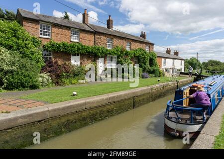 Narrowboat and lock gates on the Grand Union canal, Whilton LOcks, Northamptonshire, UK; canal-side cottages in the background Stock Photo