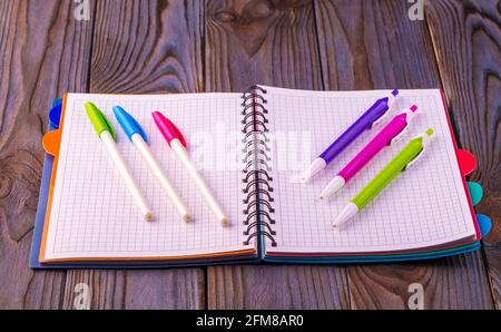 Diary (notebook) and colored pens on wooden background. Stock Photo