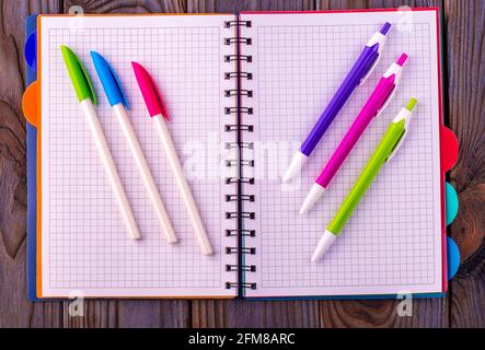 Diary (notebook) and colored pens on wooden background. Stock Photo