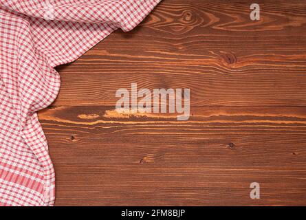 Checkered tablecloth or cloth napkin on wooden table with space for text, ideas. Top view Stock Photo