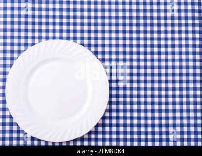 Empy plate on the tablecloth in a cage. View from above with copy space Stock Photo