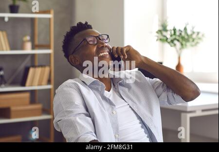 Happy black businessman holding a smartphone and having a conversation with a friend Stock Photo
